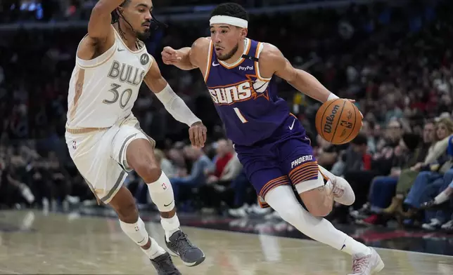 Chicago Bulls guard Tre Jones (30), left, guards Phoenix Suns guard Devin Booker (1) during the second half of an NBA basketball game Saturday, Feb. 22, 2025, in Chicago. (AP Photo/Erin Hooley)