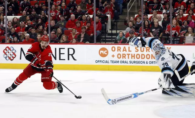 Carolina Hurricanes' Sebastian Aho (20) shoots the puck past Utah Hockey Club goaltender Karel Vejmelka (70) for a goal during the second period of an NHL hockey game in Raleigh, N.C., Saturday, Feb. 8, 2025. (AP Photo/Karl DeBlaker)