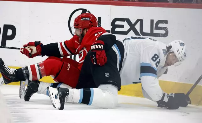 Carolina Hurricanes' Jordan Martinook (48) tangles with Utah Hockey Club's Kevin Stenlund (82) during the first period of an NHL hockey game in Raleigh, N.C., Saturday, Feb. 8, 2025. (AP Photo/Karl DeBlaker)