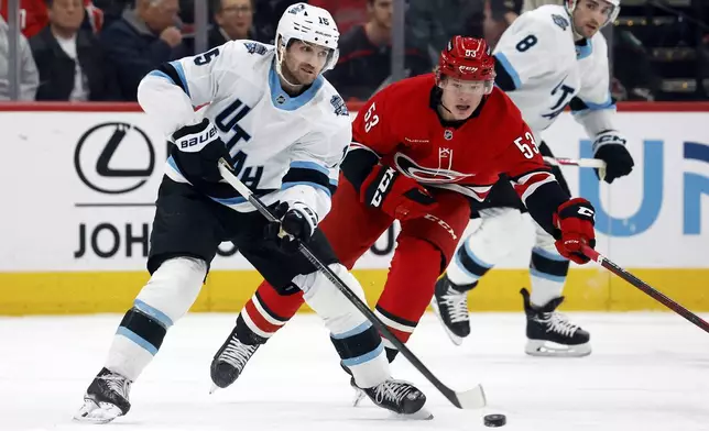 Utah Hockey Club's Alexander Kerfoot (15) moves the puck in front of Carolina Hurricanes' Jackson Blake (53) during the first period of an NHL hockey game in Raleigh, N.C., Saturday, Feb. 8, 2025. (AP Photo/Karl DeBlaker)