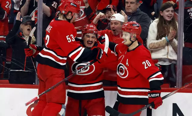 Carolina Hurricanes' Seth Jarvis, center, celebrates his goal with teammates Jackson Blake (53) and Sebastian Aho (20) during the second period of an NHL hockey game against the Utah Hockey Club in Raleigh, N.C., Saturday, Feb. 8, 2025. (AP Photo/Karl DeBlaker)