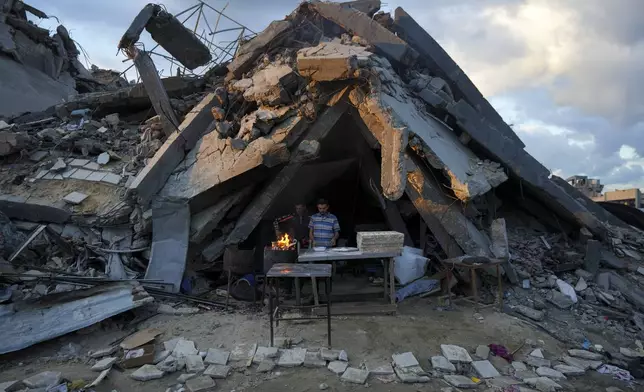 A man sells bread under the destruction of his bakery destroyed by the Israeli air and ground offensive in Jabaliya, Gaza Strip, Wednesday, Feb. 5, 2025. (AP Photo/Abdel Kareem Hana)