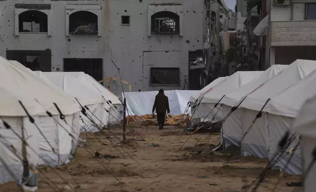 A man walks between tents for displaced Palestinians next to destroyed buildings following the Israeli air and ground offensive in Jabaliya, Gaza Strip, Thursday, Feb. 6, 2025. (AP Photo/Abdel Kareem Hana)