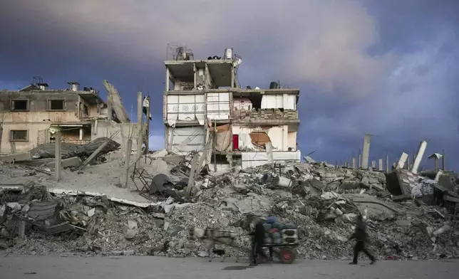A man pushes a cart past a house that remains partly standing, but with sheets serving as makeshift walls, in an area largely destroyed by the Israeli army's air and ground offensive in Gaza City, Gaza Strip, Wednesday, Feb. 5, 2025. (AP Photo/Abdel Kareem Hana)