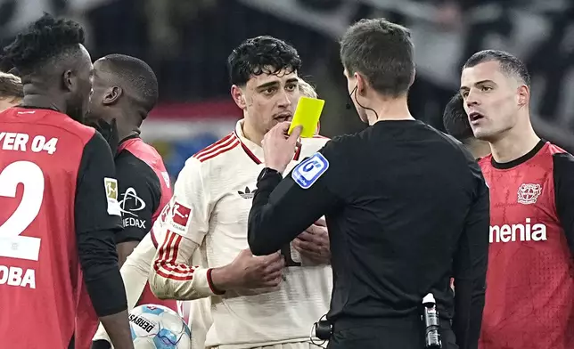 Referee Samuel Barrott shows a yellow card to Bayern's Aleksandar Pavlovic during the German Bundesliga soccer match between Bayer Leverkusen and FC Bayern Munich at the BayArena in Leverkusen, Germany, Saturday, Feb. 15, 2025. (AP Photo/Martin Meissner)