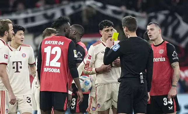 Referee Samuel Barrott shows a yellow card to Bayern's Aleksandar Pavlovic during the German Bundesliga soccer match between Bayer Leverkusen and FC Bayern Munich at the BayArena in Leverkusen, Germany, Saturday, Feb. 15, 2025. (AP Photo/Martin Meissner)