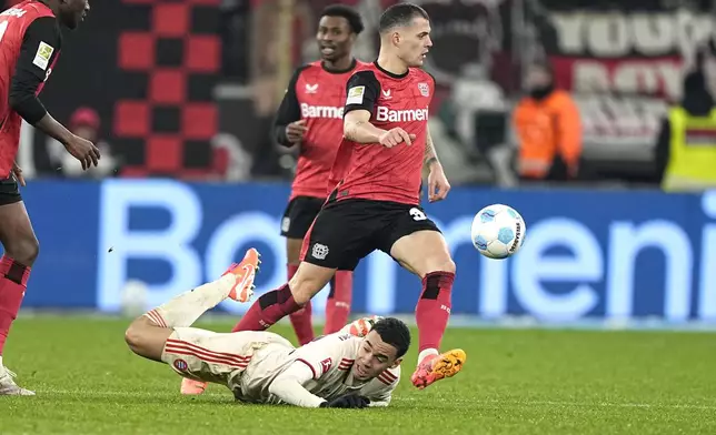 Bayern's Jamal Musiala, bottom, challenges for the ball with Leverkusen's Granit Xhaka during the German Bundesliga soccer match between Bayer Leverkusen and FC Bayern Munich at the BayArena in Leverkusen, Germany, Saturday, Feb. 15, 2025. (AP Photo/Martin Meissner)