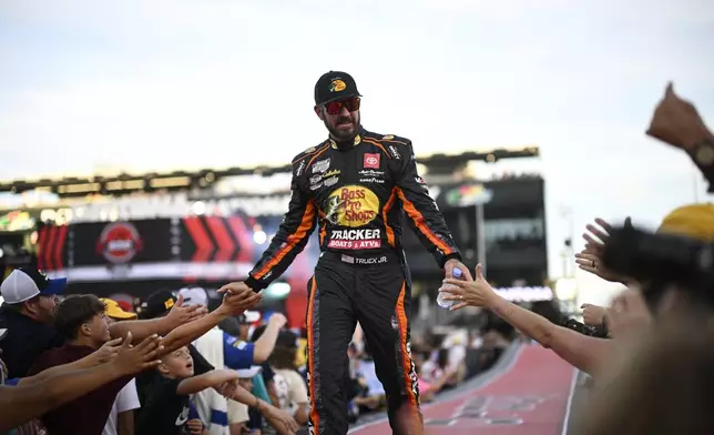 FILE Martin Truex Jr. interacts with spectators while walking down a runway during driver introductions before a NASCAR Cup Series auto race at Daytona International Speedway, Aug. 24, 2024, in Daytona Beach, Fla. (AP Photo/Phelan M. Ebenhack, file)