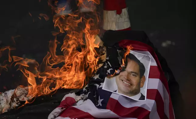 A photo of U.S. Secretary of State Marco Rubio is burned by demonstrators protesting his upcoming visit to Panama City, Friday, Jan. 31, 2025. (AP Photo/Matias Delacroix)