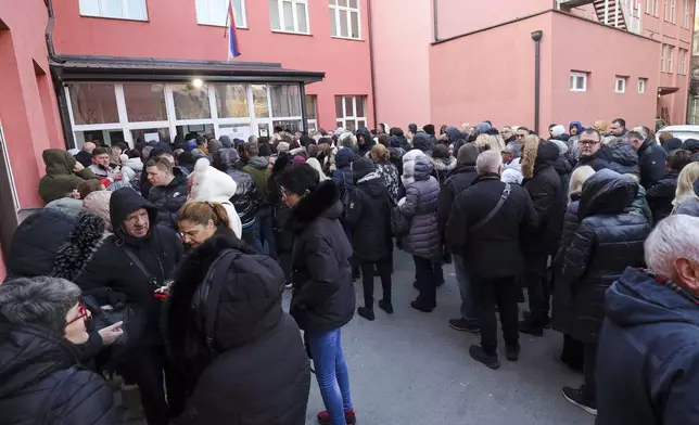 People wait in front of a polling station for a parliamentary election in the northern Serb-dominated part of ethnically divided town of Mitrovica, Kosovo, Sunday, Feb. 9, 2025. (AP Photo/Bojan Slavkovic)