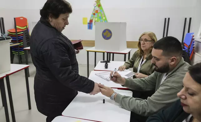 A woman is checked by a member of an electoral committee during a parliamentary election in Pristina, Kosovo, Sunday, Feb. 9, 2025. (AP Photo/Vlasov Sulaj)