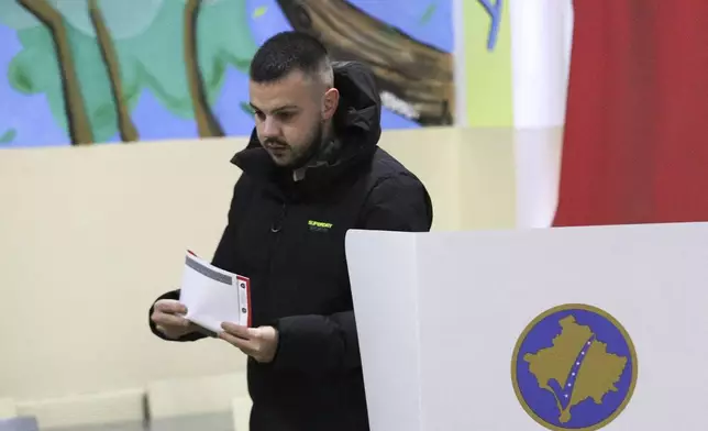 A man prepares his ballot for a parliamentary election at a polling station in the northern Serb-dominated part of ethnically divided town of Mitrovica, Kosovo, Sunday, Feb. 9, 2025. (AP Photo/Bojan Slavkovic)
