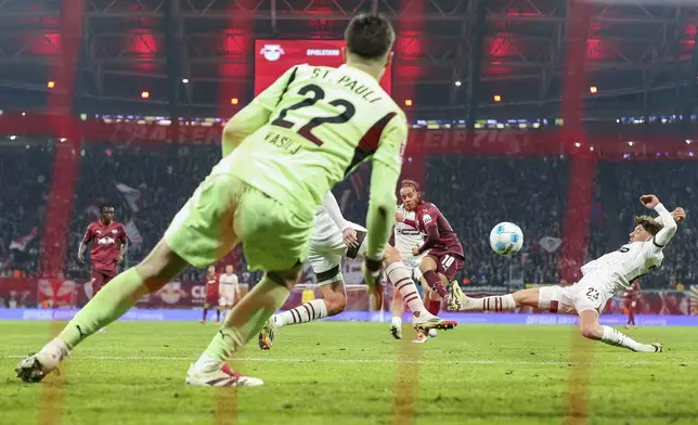 Leipzig's Xavi Simons, center, scores against St. Pauli goalkeeper Nikola Vasilj during a Bundesliga soccer match in Leipzig, Germany, Sunday, Feb. 9, 2025. (Jan Woitas/dpa via AP)