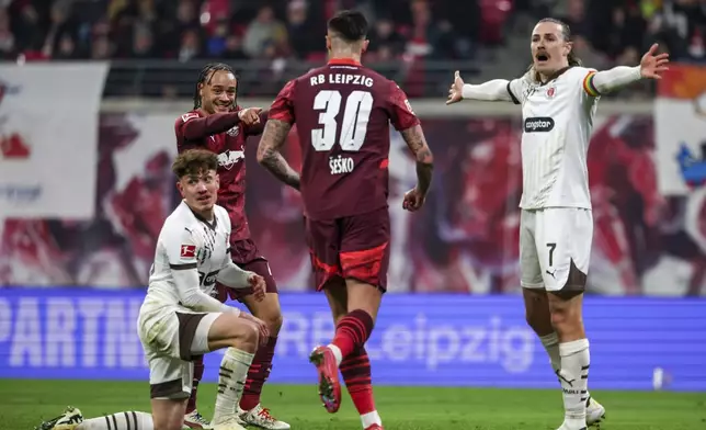Leipzig's Xavi Simons, left, cheers for Benjamin Sesko, center, after scoring as St. Pauli's Philipp Treu, left, and Jackson Irvine react during a Bundesliga soccer match in Leipzig, Germany, Sunday, Feb. 9, 2025. (Jan Woitas/dpa via AP)