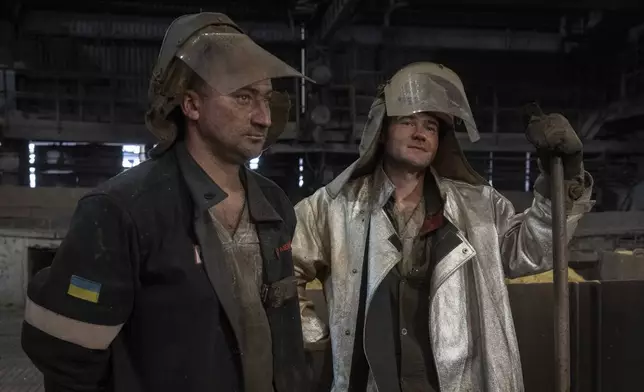 Steel melting workers chat at work at the Zaporizhstal Iron and Steelworks, one of the country's largest steel plants, in Zaporizhzhia, Ukraine, Thursday, Feb. 13, 2025. (AP Photo/Efrem Lukatsky)