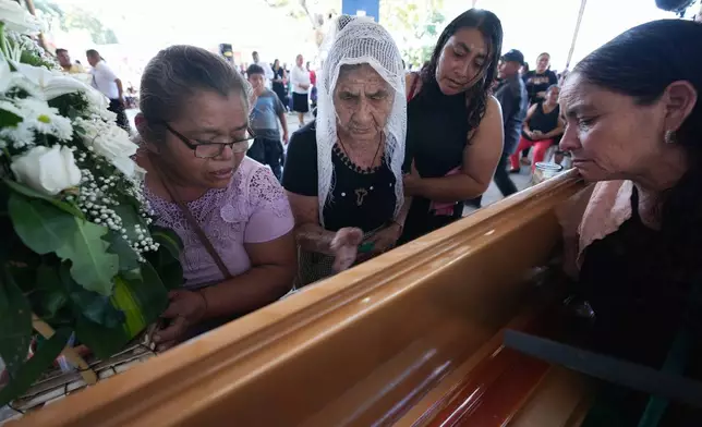 Mourners pay their final respects to the victim of a bus crash at a funeral service in Santo Domingo Los Ocotes, Guatemala, Tuesday, Feb. 11, 2025. Dozens of passengers died after their bus plunged into a gorge and landed under a bridge on Feb. 10 on the outskirts of the Guatemalan capital. (AP Photo/Moises Castillo)