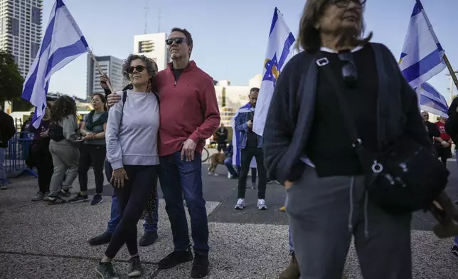 Israelis watch a broadcast of the release of Israelis Ofer Kalderon, 53, and Yarden Bibas, 34, and American-Israeli Keith Siegel, 65 set to be released as part of a ceasefire in the Gaza Strip, in Tel Aviv, Israel, Saturday Feb. 1, 2025. (AP Photo/Oded Balilty)