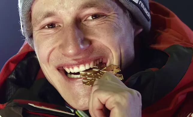 Switzerland's Marco Odermatt bites his gold medal for a men's Super-G, at the Alpine Ski World Championships, in Saalbach-Hinterglemm, Austria, Friday, Feb. 7, 2025. (AP Photo/Gabriele Facciotti)
