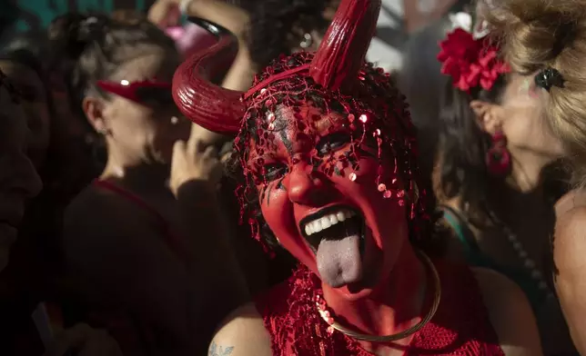 A reveler dressed as a devil sticks out her tongue during the "Ceu na Terra" or "Heaven on Earth" pre-Carnival street party, in Rio de Janeiro, Saturday, Feb. 22, 2025. (AP Photo/Bruna Prado)