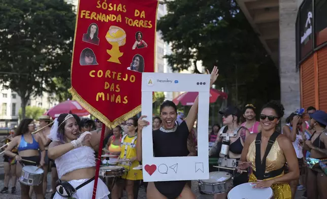 A reveler dressed as Oscar-nominated actress Fernanda Torres holds a cutout of an Instagram account of "The Academy" during a pre-Carnival lookalike event in Rio de Janeiro, Sunday, Feb. 23, 2025. (AP Photo/Silvia Izquierdo)
