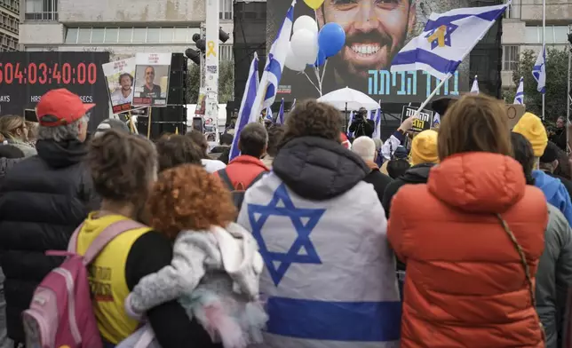 Israelis watch on a live broadcast as the first two of six hostages to be released in Gaza by Palestinian militants are handed over to the Red Cross, in 'Hostages Square' in Tel Aviv, Israel, Saturday Feb. 22, 2025. (AP Photo/Oded Balilty)