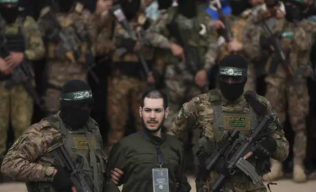 Israeli hostage Eliya Cohen, centre, is escorted by Hamas fighters before being handed over to the Red Cross in Nuseirat, central Gaza Strip, Saturday, Feb. 22, 2025. (AP Photo/Abdel Kareem Hana)