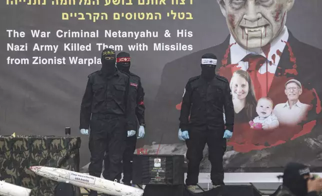 Palestinian fighters stand next to a coffin containing the body of Oded Lifshitz, as the remains of four bodies are handed over to the Red Cross in Khan Younis, southern Gaza Strip, Thursday, Feb. 20, 2025. Israel has identified three of the bodies as hostages and said the other was of an unknown person. (AP Photo/Jehad Alshrafi)