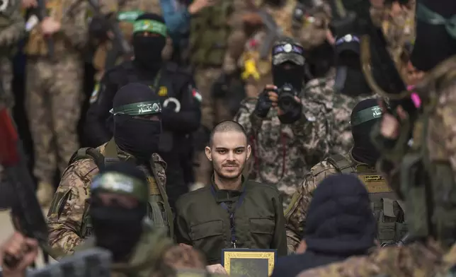Israeli hostage Omer Wenkert, centre, is escorted by Hamas fighters before being handed over to the Red Cross in Nuseirat, central Gaza Strip, Saturday, Feb. 22, 2025. (AP Photo/Abdel Kareem Hana)