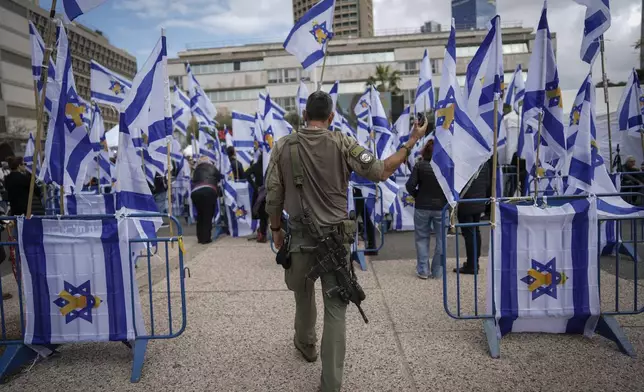 An Israeli soldier holds his cellphone as he walks into "Hostages Square" in Tel Aviv, Israel, Thursday, Feb. 20, 2025, as Palestinian militant groups hand over the bodies of four Israeli hostages, including a mother and her two children, to the Red Cross in Gaza.(AP Photo/Oded Balilty)