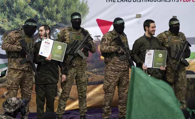 Israeli hostages Eliya Cohen, left, and Omer Shem Tov are escorted by Hamas fighters before being handed over to the Red Cross in Nuseirat, central Gaza Strip, Saturday, Feb. 22, 2025. (AP Photo/Abdel Kareem Hana)