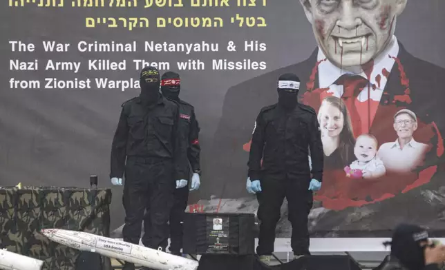 Palestinian fighters stand next to a coffin containing the body of Oded Lifshitz, one of four Israeli hostages, to hand it over to the Red Cross in Khan Younis, southern Gaza Strip, Thursday, Feb. 20, 2025. (AP Photo/Jehad Alshrafi)