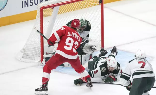 Detroit Red Wings right wing Alex DeBrincat (93) shoots but hits the pipes as Minnesota Wild goaltender Marc-Andre Fleury (29) defends in the second period of an NHL hockey game Saturday, Feb. 22, 2025, in Detroit. (AP Photo/Paul Sancya)