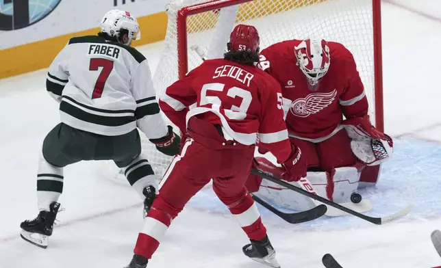 Detroit Red Wings goaltender Cam Talbot (39) stops a Minnesota Wild defenseman Brock Faber (7) shot as Moritz Seider (53) defends in the first period of an NHL hockey game Saturday, Feb. 22, 2025, in Detroit. (AP Photo/Paul Sancya)