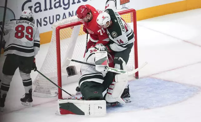 Detroit Red Wings center Dylan Larkin (71) scores on Minnesota Wild goaltender Marc-Andre Fleury (29) as Joel Eriksson Ek (14) defends in the second period of an NHL hockey game Saturday, Feb. 22, 2025, in Detroit. (AP Photo/Paul Sancya)