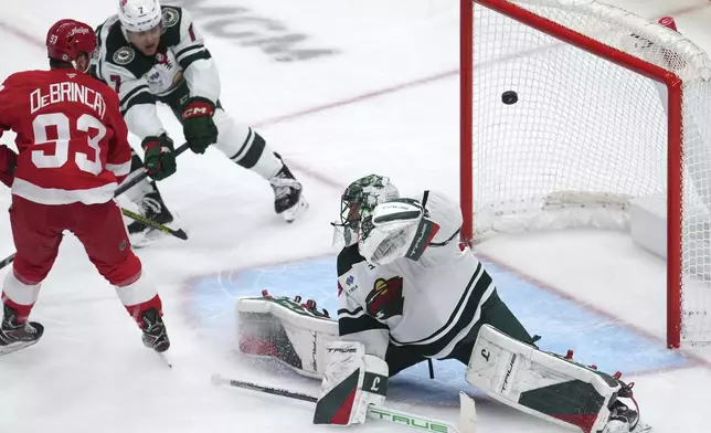 Detroit Red Wings right wing Alex DeBrincat (93) scores past Minnesota Wild goaltender Marc-Andre Fleury (29) in the first period of an NHL hockey game Saturday, Feb. 22, 2025, in Detroit. (AP Photo/Paul Sancya)
