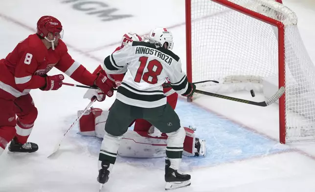 Minnesota Wild center Vinnie Hinostroza (18) scores on Detroit Red Wings goaltender Cam Talbot (39) as Ben Chiarot (8) defends in the second period of an NHL hockey game Saturday, Feb. 22, 2025, in Detroit. (AP Photo/Paul Sancya)