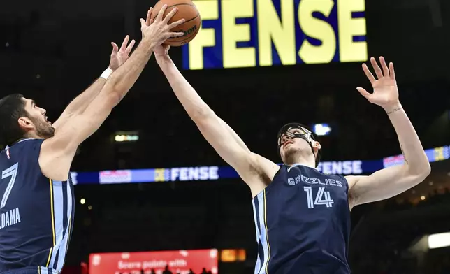Memphis Grizzlies forward Santi Aldama (7) and center Zach Edey (14) reach for a rebound in the first half of an NBA basketball game against the San Antonio Spurs, Monday, Feb. 3, 2025, in Memphis, Tenn. (AP Photo/Brandon Dill)