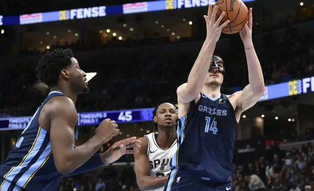 Memphis Grizzlies center Zach Edey (14) handles the ball ahead of San Antonio Spurs center Charles Bassey, center, and forward Jaren Jackson Jr., left, in the first half of an NBA basketball game Monday, Feb. 3, 2025, in Memphis, Tenn. (AP Photo/Brandon Dill)