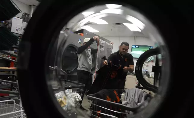 Arturo Maya, right, and Riley Halpin, left, inspect and sort laundry in the San Francisco Giants laundry room during spring training baseball practice at the team's facility, Monday, Feb. 17, 2025, in Scottsdale, Ariz. (AP Photo/Carolyn Kaster)