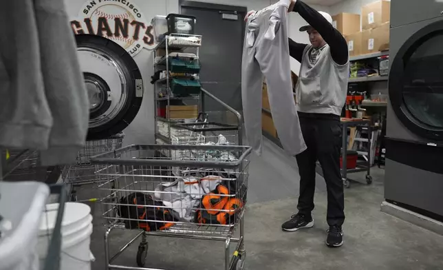 San Francisco Giants clubhouse attendant Riley Halpin inspects baseball pants for stains and pine tar in the laundry room during baseball spring training at the team's facility, Monday, Feb. 17, 2025, in Scottsdale, Ariz. (AP Photo/Carolyn Kaster)