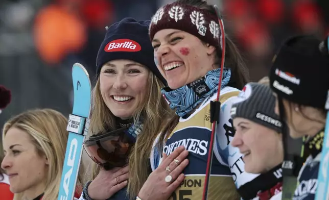 United States' Mikaela Shiffrin, center left, and teammate United States' Breezy Johnson celebrate on the podium after winning the gold medal in a women's team combined event, at the Alpine Ski World Championships, in Saalbach-Hinterglemm, Austria, Tuesday, Feb. 11, 2025. (AP Photo/Marco Trovati)