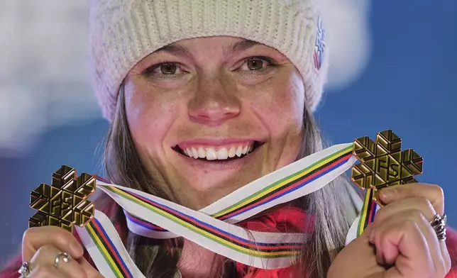 United States' Breezy Johnson shows her gold medal for a women's downhill and for a women's team combined event, at the Alpine Ski World Championships, in Saalbach-Hinterglemm, Austria, Tuesday, Feb. 11, 2025. (AP Photo/Giovanni Auletta)