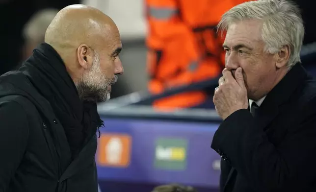Real Madrid's head coach Carlo Ancelotti, right, talks to Manchester City's head coach Pep Guardiola before the start of the Champions League playoff first leg soccer match between Manchester City and Real Madrid at the Etihad Stadium in Manchester, England, Tuesday, Feb. 11, 2025. (AP Photo/Dave Thompson)