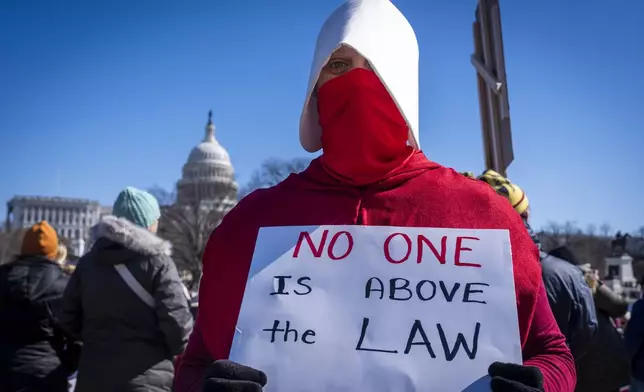 Shannon Perry, a special education teacher from Centreville, Va., wears a handmaids costume while attending a "No Kings Day" protest on Presidents Day in Washington, in support of federal workers and against recent actions by President Donald Trump and Elon Musk, Monday, Feb. 17, 2025, by the Capitol in Washington. The protest was organized by the 50501 Movement, which stands for 50 Protests 50 States 1 Movement. (AP Photo/Jacquelyn Martin)