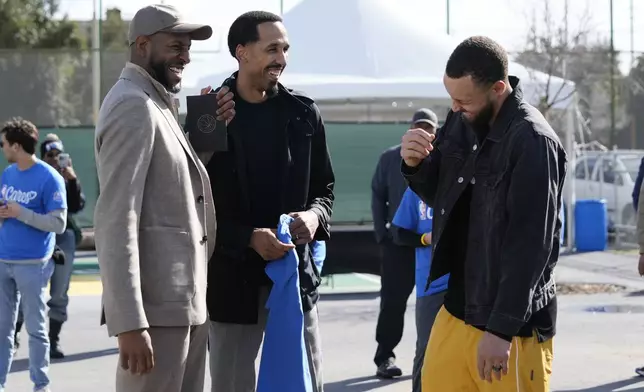 Stephen Curry, right, talks to his ex-teammates Andre Igoudala and Shaun Livingston during a visit to East Oakland Pride Elementary School as part of the NBA basketball league's Day of Service, Friday, Feb. 14, 2025, Oakland, Calif. (AP Photo/Godofredo A. Vásquez)