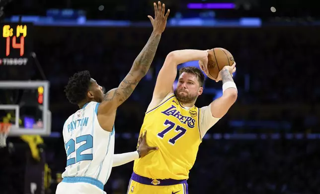 Los Angeles Lakers guard Luka Doncic (77) looks to pass the ball while under pressure from Charlotte Hornets guard Elfrid Payton (22) during the second half of an NBA basketball game Wednesday, Feb. 19, 2025, in Los Angeles. (AP Photo/William Liang)