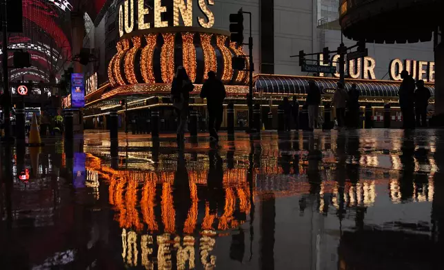 People walk along Fremont Street in the rain Thursday, Feb. 13, 2025, in Las Vegas. (AP Photo/John Locher)