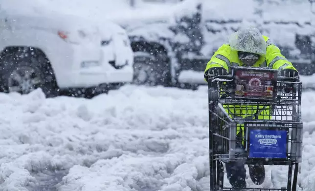 A person pushes a shopping cart on a snow-covered parking lot during a storm Thursday, Feb. 13, 2025, in Truckee, Calif. (AP Photo/Brooke Hess-Homeier)