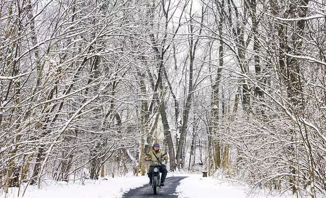 Jose Escobar rides his motorized bicycle on the trails in Rock Creek Park in Frederick, Md. on Wednesday, Feb. 12, 2025, after snowfall overnight. Parts of the area received 2-4 inches of snow. (Ric Dugan/The Frederick News-Post via AP)