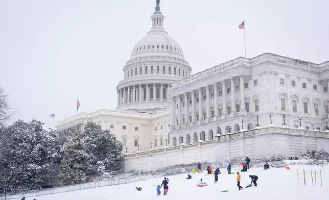 Families enjoy the snow by the Capitol, Wednesday, Feb. 12, 2025, as they sled after a snowstorm in Washington. (AP Photo/Jacquelyn Martin)